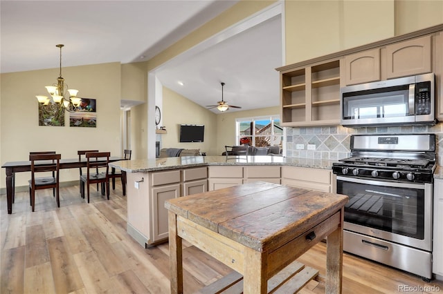 kitchen featuring light wood finished floors, stainless steel appliances, a peninsula, and lofted ceiling