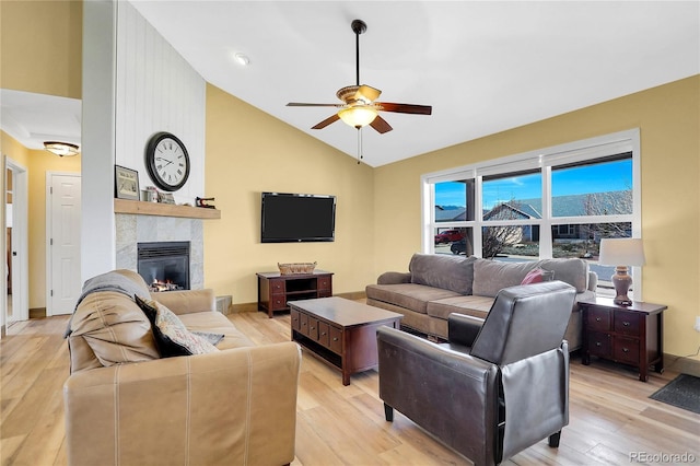 living room with baseboards, light wood finished floors, ceiling fan, and a fireplace