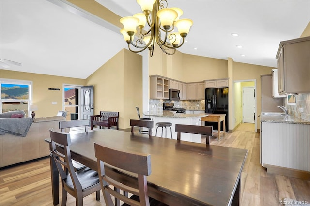 dining space featuring light wood finished floors, a chandelier, and high vaulted ceiling