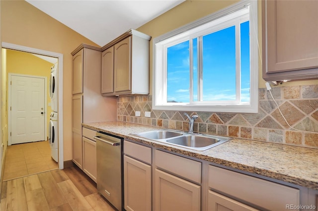 kitchen with stacked washer and dryer, decorative backsplash, light countertops, a sink, and dishwasher
