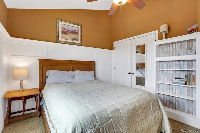 bedroom featuring a ceiling fan, a wainscoted wall, a closet, a decorative wall, and carpet flooring