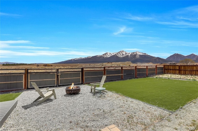 view of yard with a fenced backyard, an outdoor fire pit, and a mountain view