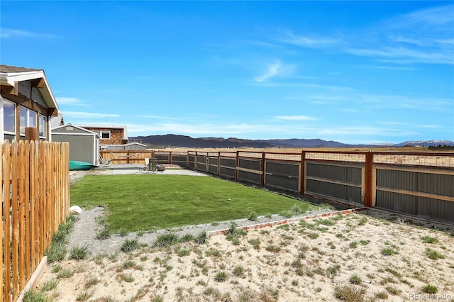 view of yard featuring a storage shed, an outdoor structure, a mountain view, and a fenced backyard
