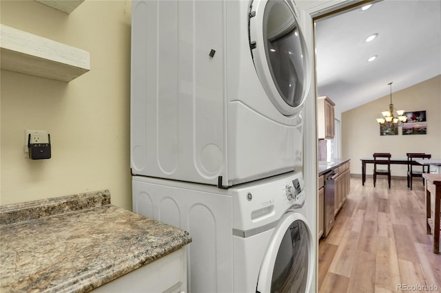 laundry area with an inviting chandelier, recessed lighting, light wood-type flooring, and stacked washer / dryer