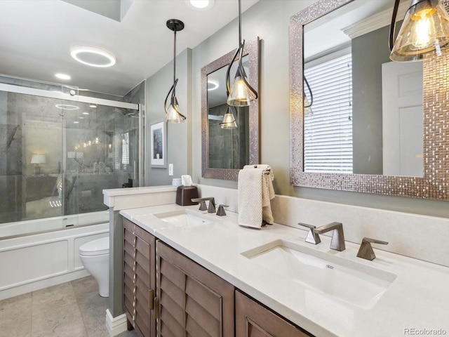 bathroom featuring double vanity, enclosed tub / shower combo, toilet, and a sink