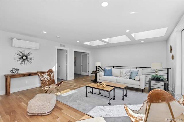 living room with a wall mounted air conditioner, a skylight, and light hardwood / wood-style floors