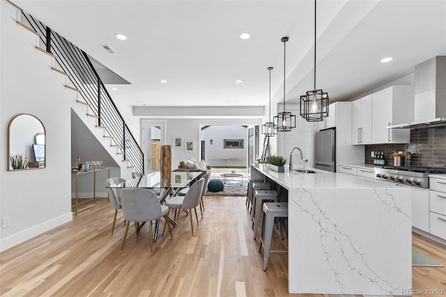 kitchen featuring white cabinetry, appliances with stainless steel finishes, wall chimney range hood, and a spacious island