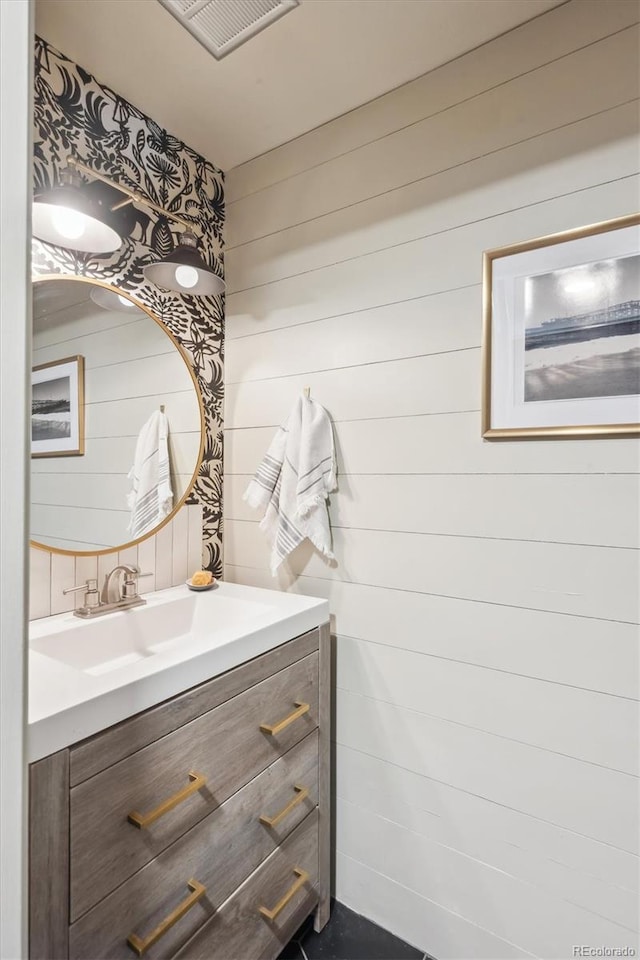 bathroom featuring visible vents, wood walls, and vanity