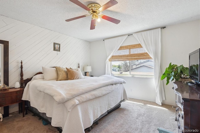 carpeted bedroom with a ceiling fan, wood walls, and a textured ceiling