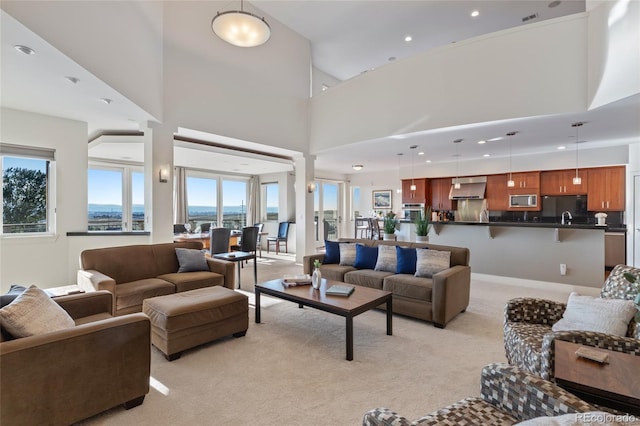 carpeted living room with a high ceiling and sink