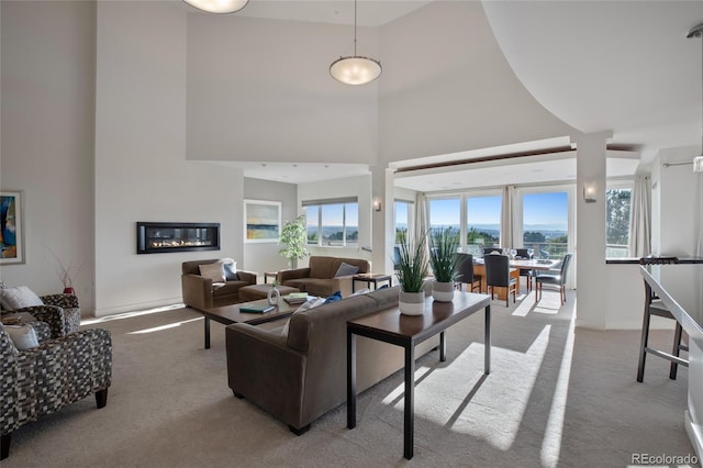 carpeted living room featuring a towering ceiling and a wealth of natural light