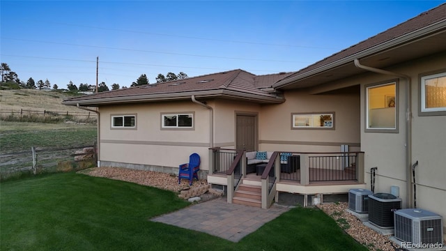 rear view of house featuring cooling unit, a yard, and a wooden deck