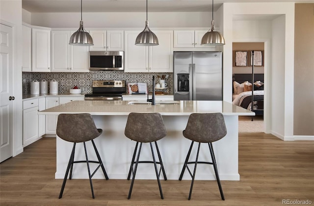 kitchen with appliances with stainless steel finishes, sink, a center island with sink, and white cabinets