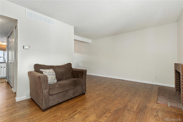 sitting room featuring hardwood / wood-style flooring, a fireplace, and a textured ceiling