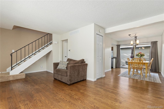 living room featuring hardwood / wood-style floors, a textured ceiling, and a notable chandelier