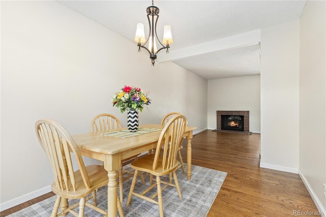 dining room with an inviting chandelier, a fireplace, dark hardwood / wood-style flooring, and a textured ceiling