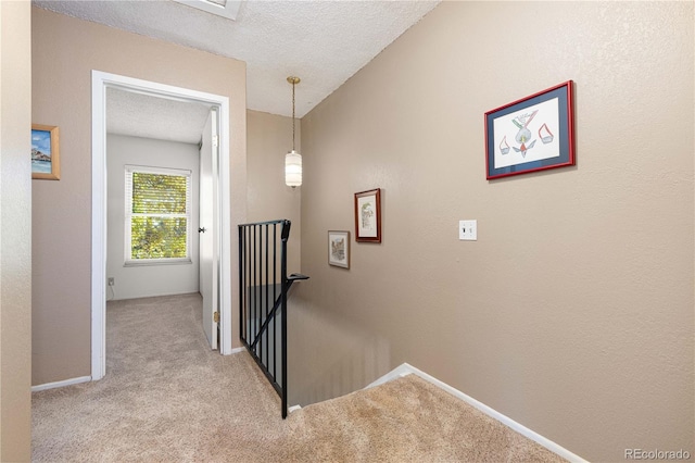 corridor featuring light carpet and a textured ceiling