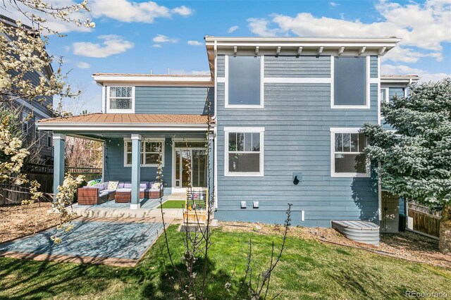 back of property with an outdoor hangout area, fence, and a lawn