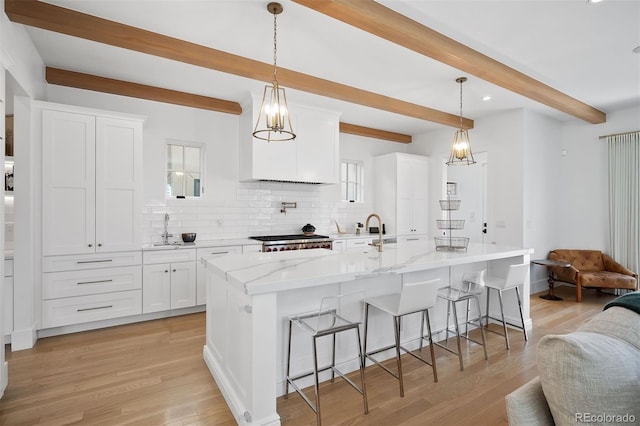 kitchen featuring beam ceiling, backsplash, open floor plan, a breakfast bar, and white cabinets