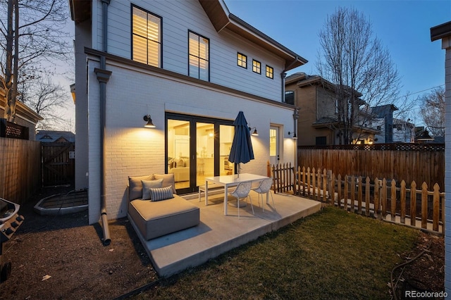 rear view of house with brick siding, a patio, a fenced backyard, and a gate