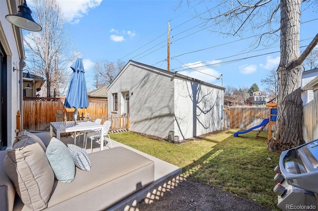 view of yard featuring outdoor dining area, a patio, an outdoor structure, and a playground
