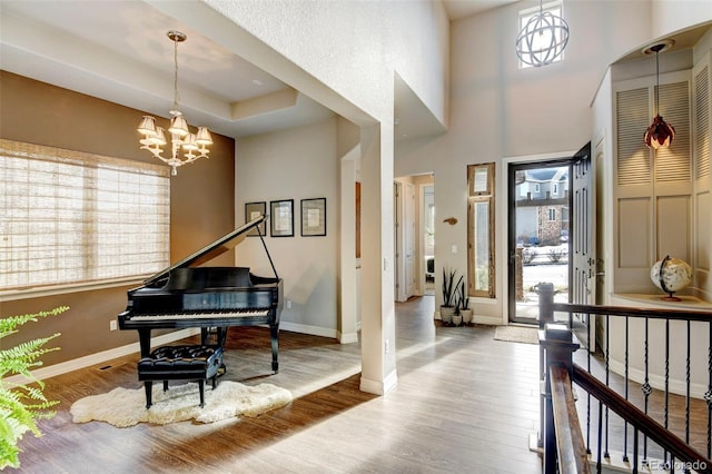 entryway with a tray ceiling, a chandelier, and hardwood / wood-style flooring