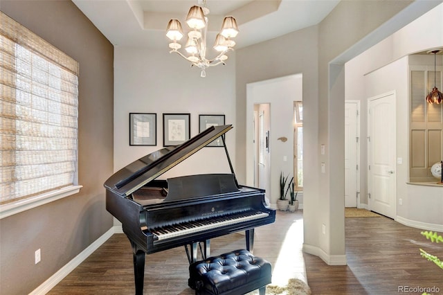 misc room with a chandelier, a raised ceiling, and dark wood-type flooring