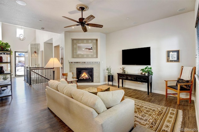 living room featuring ceiling fan, a fireplace, and dark hardwood / wood-style floors