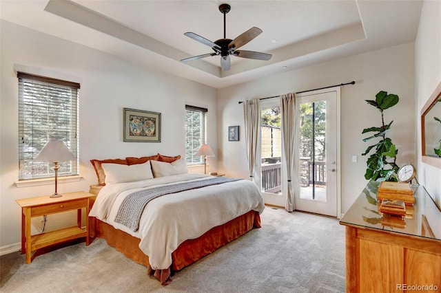 bedroom featuring a tray ceiling, access to exterior, ceiling fan, and light colored carpet