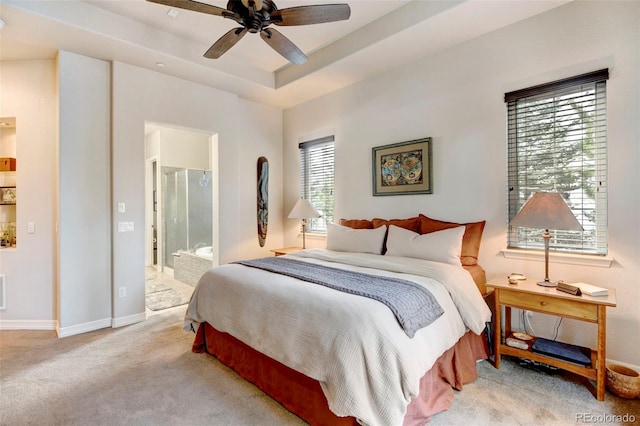 bedroom featuring a tray ceiling, connected bathroom, ceiling fan, and light colored carpet