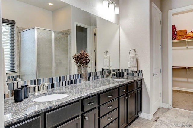 bathroom featuring tile patterned flooring, decorative backsplash, an enclosed shower, and vanity