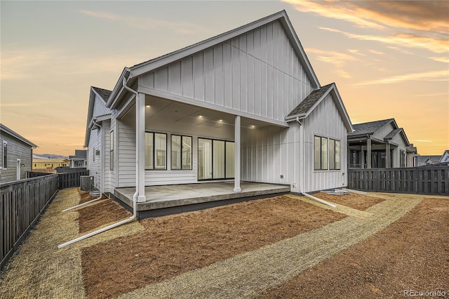 back house at dusk with cooling unit and a patio