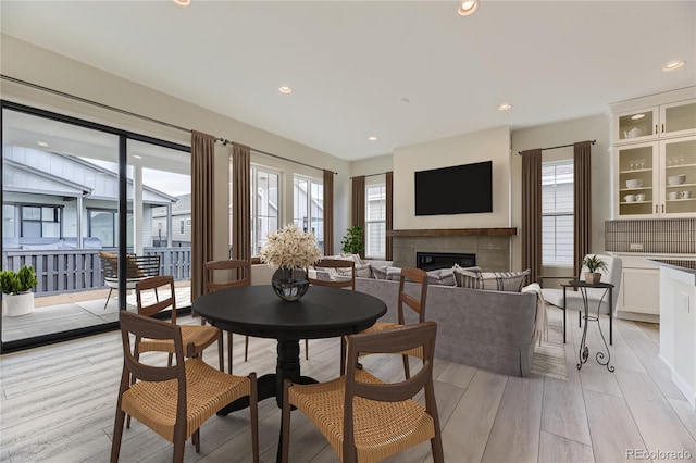 dining area featuring light wood-type flooring and a tiled fireplace