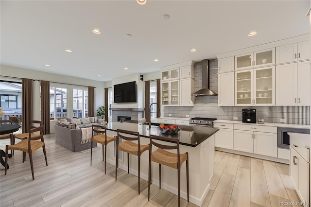 kitchen featuring high end stainless steel range, wall chimney range hood, white cabinets, and a kitchen island