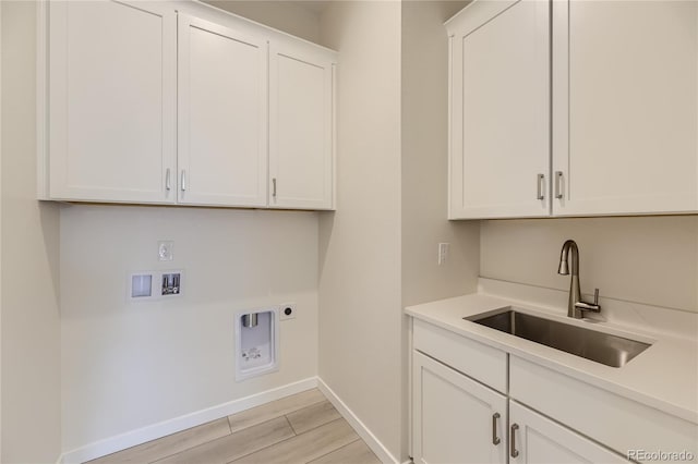 washroom featuring electric dryer hookup, sink, cabinets, light hardwood / wood-style floors, and washer hookup