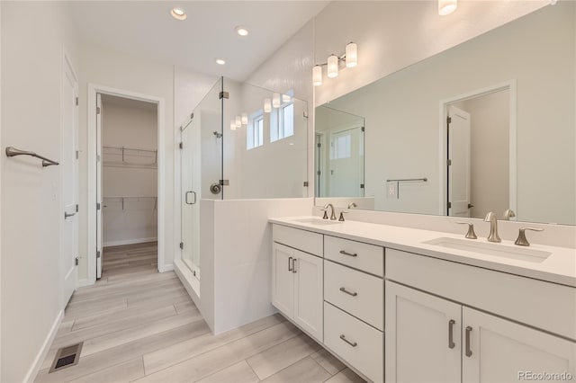 bathroom with vanity, hardwood / wood-style flooring, and a shower with door