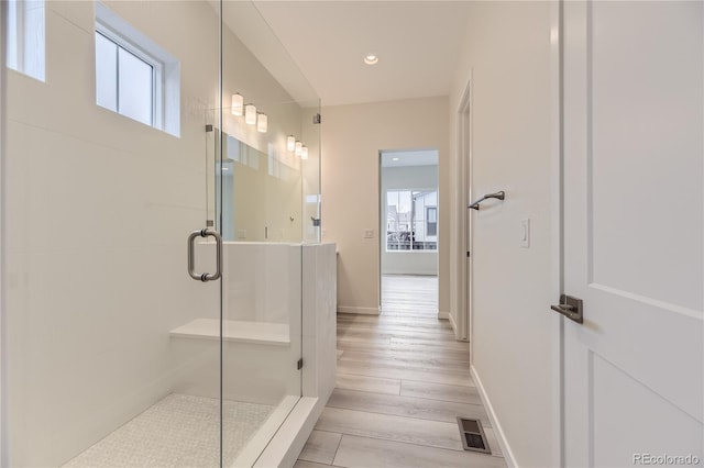 bathroom with a shower with door and wood-type flooring