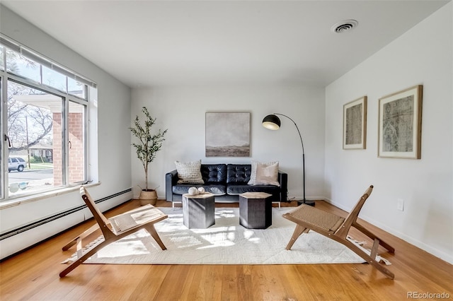 living room with baseboards, baseboard heating, visible vents, and wood finished floors