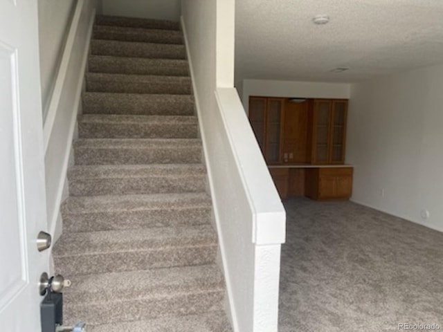 stairs with carpet flooring and a textured ceiling