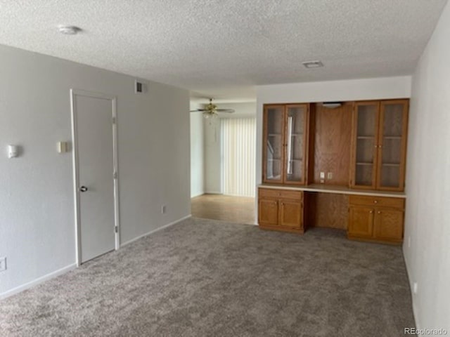 unfurnished living room with carpet flooring, ceiling fan, and a textured ceiling