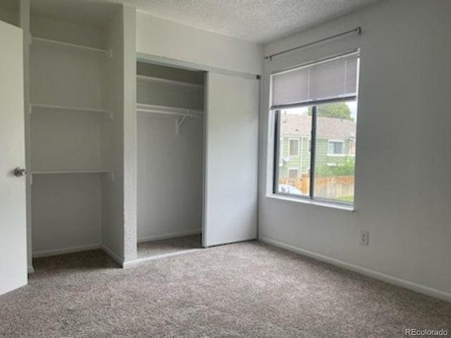 unfurnished bedroom featuring carpet flooring, a textured ceiling, and a closet