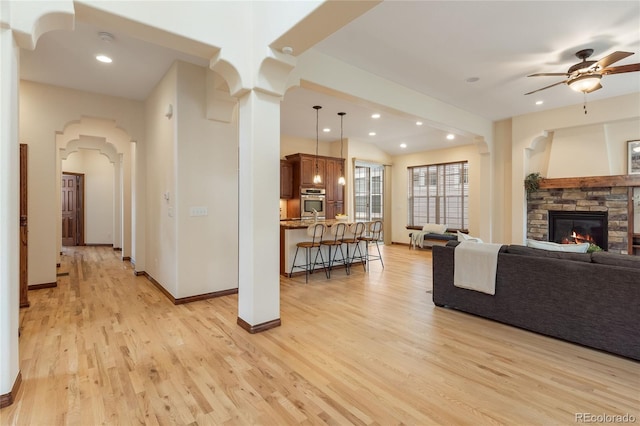 5723 S Union Ct, Littleton, CO 80127 - living room featuring light wood-style flooring, a stone fireplace, ceiling fan, arched walkways, and recessed lighting