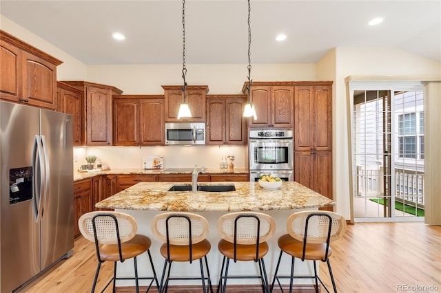 5723 S Union Ct, Littleton, CO 80127 - kitchen featuring appliances with stainless steel finishes, an island with sink, light wood finished floors, a breakfast bar, and recessed lighting