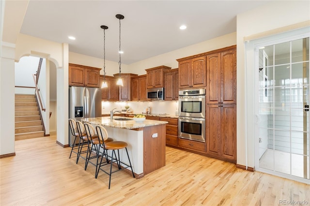 5723 S Union Ct, Littleton, CO 80127 - kitchen with stainless steel appliances, light wood-style floors, a kitchen island with sink, light stone countertops, and recessed lighting