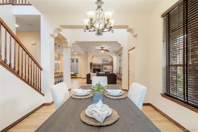 5723 S Union Ct, Littleton, CO 80127 - dining room featuring arched walkways, light wood finished floors, a stone fireplace, and a chandelier
