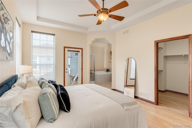 5723 S Union Ct, Littleton, CO 80127 - bedroom with arched walkways, a raised ceiling, light wood-style floors, a walk in closet, and connected bathroom
