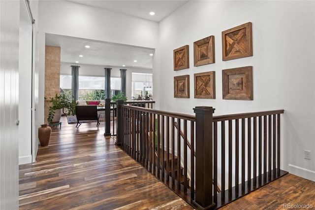 hallway with recessed lighting, wood finished floors, and an upstairs landing