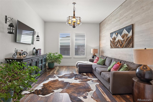 living area featuring an inviting chandelier, baseboards, an accent wall, and wood-type flooring