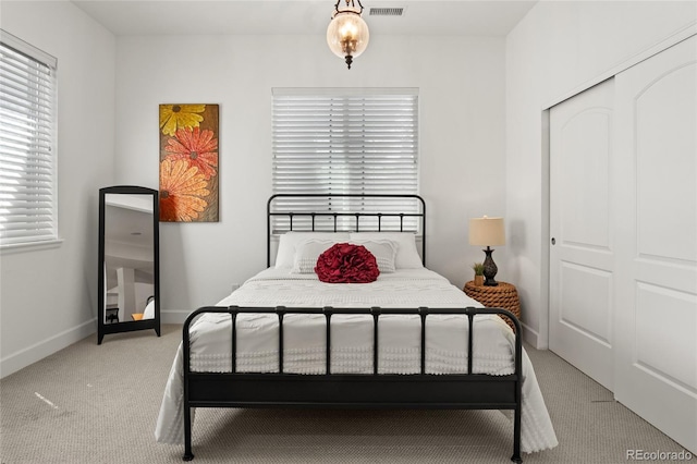 bedroom featuring a closet, baseboards, visible vents, and light carpet
