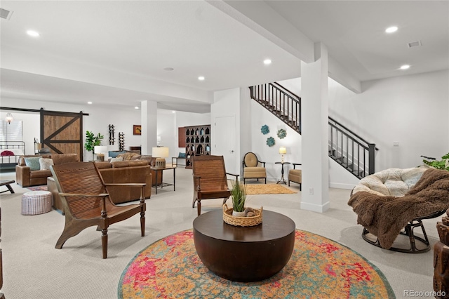 living room featuring light colored carpet, a barn door, recessed lighting, visible vents, and stairway